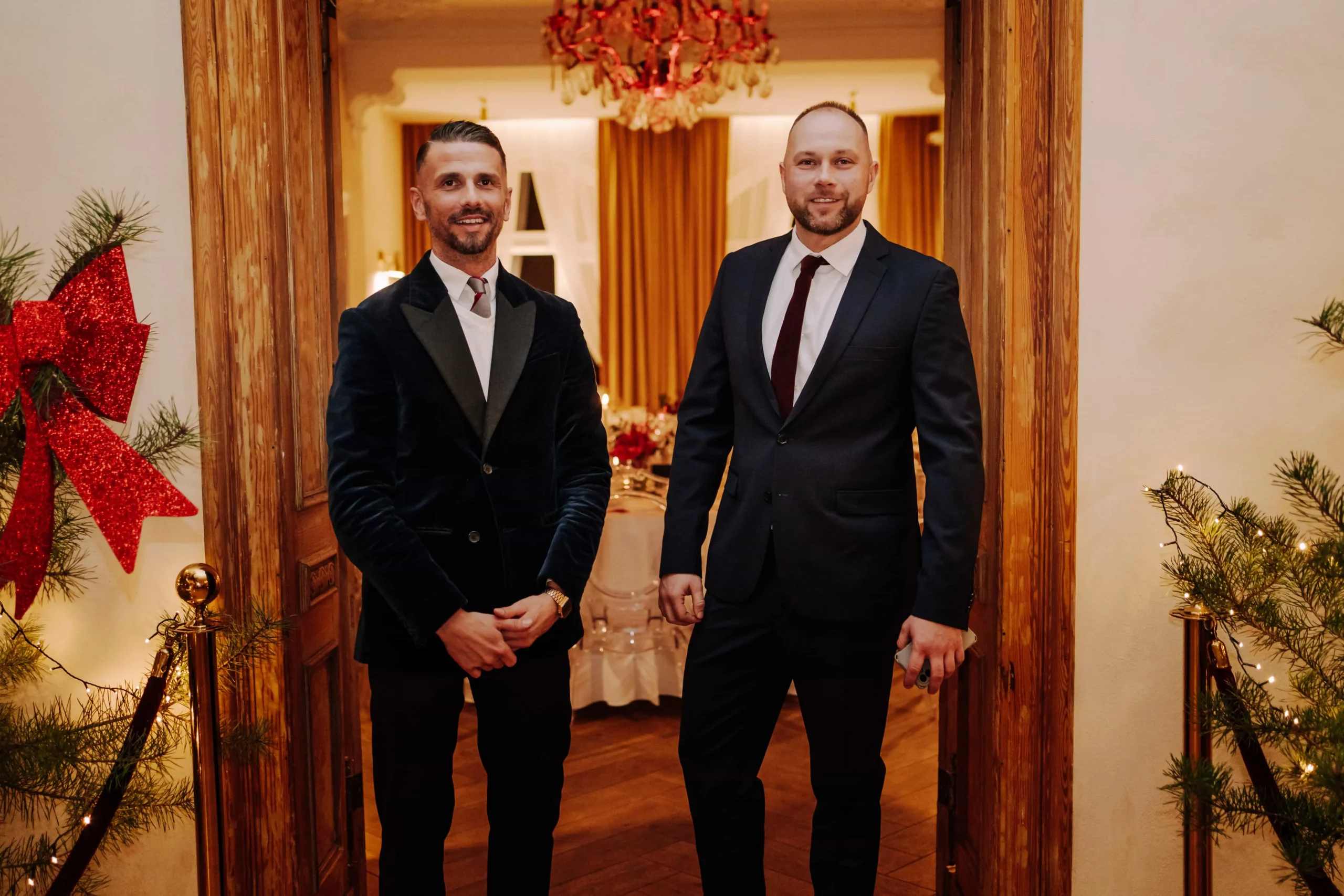 Robert Okuliński i Artur Gryś w garniturach przy wejściu do udekorowanej świątecznie sali w Willi Berlińskiej